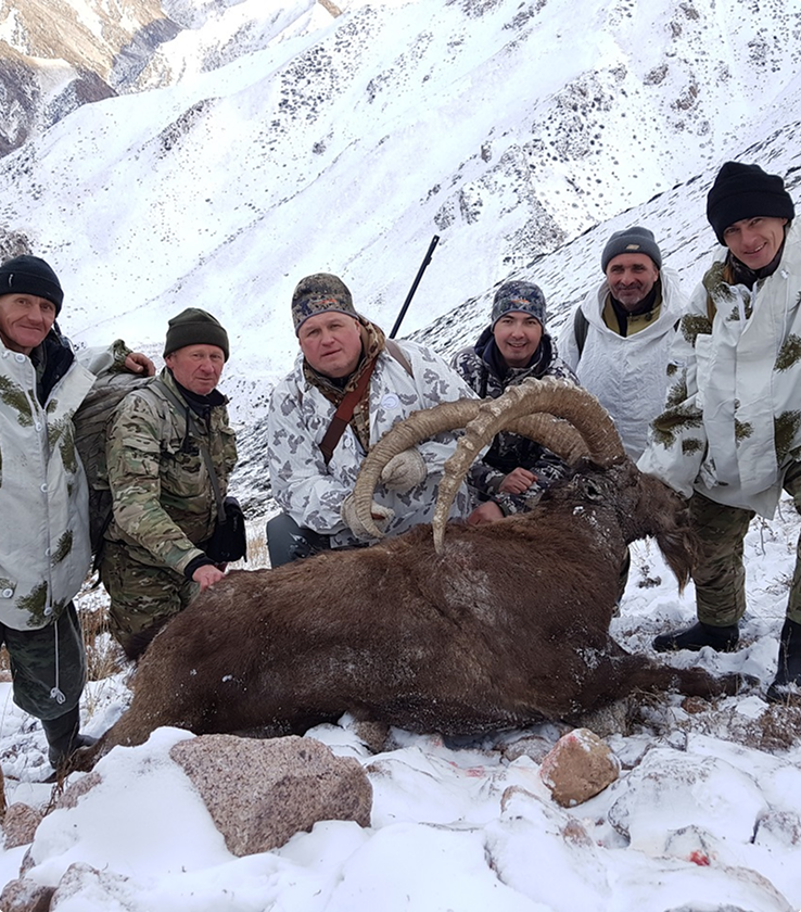 Group of hunters in winter camouflage with large trophy