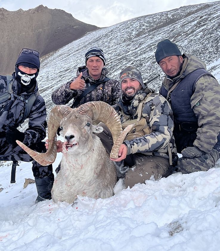 Hunters with mountain goat trophy in snowy conditions