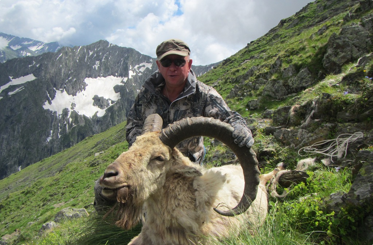 Hunter with trophy animal in mountainous landscape